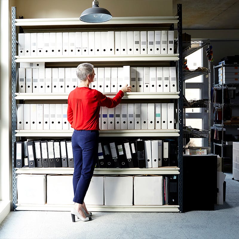 Business woman reaching for a file in an office