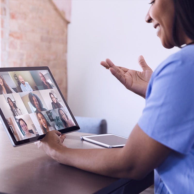 A confident female healthcare professional gestures as she talks with a medical team via video conference