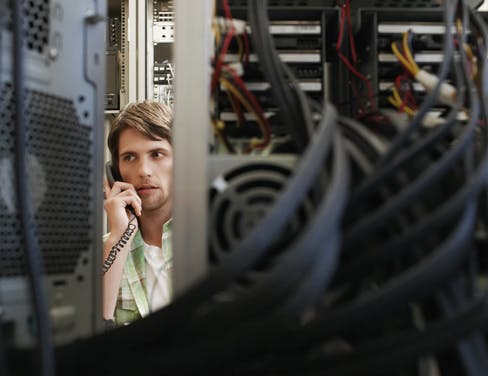 IT worker on his phone in a server room