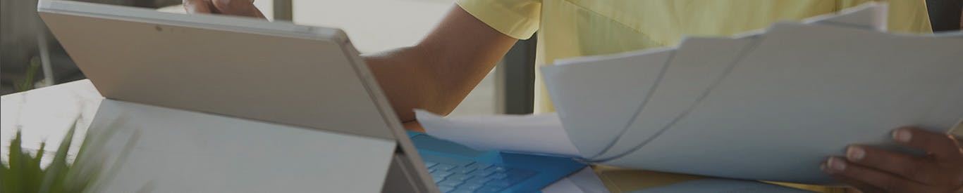 woman working on a laptop comparing with printed documents