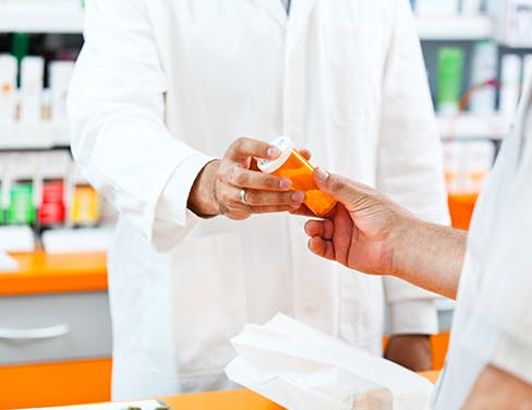 Pharmacist giving medication to customer.