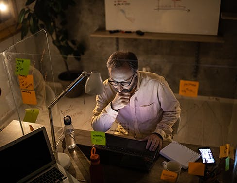 man on computer surrounded by post-it notes