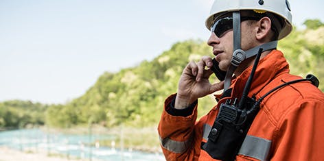 man in field with hard hat talking on a mobile phone