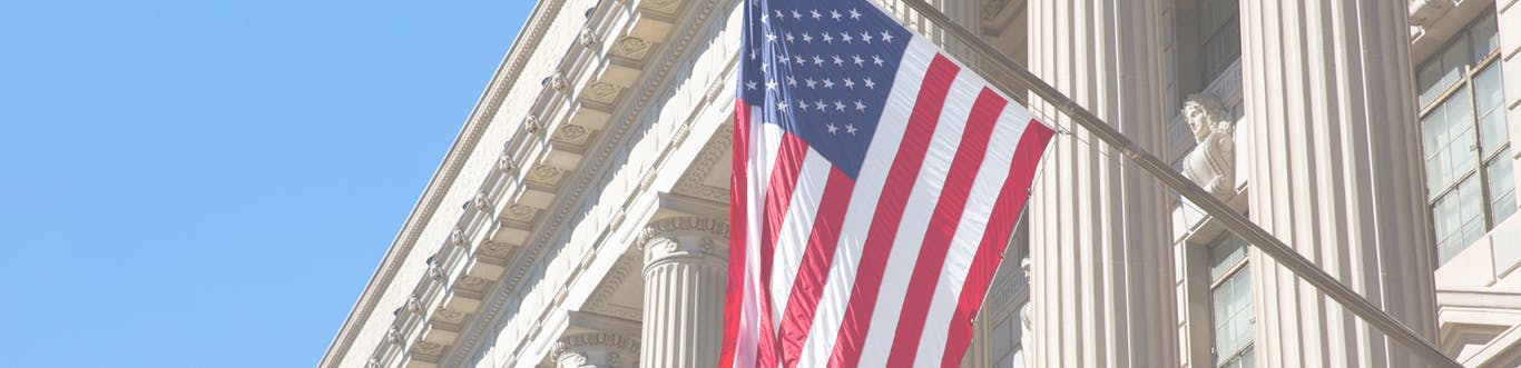 Close up of USA flag with courthouse columns in background and blue sky