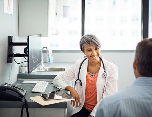 Happy female doctor talking to male patient in neurological clinic