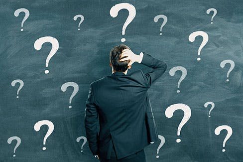 businessman looking at  wall of question marks