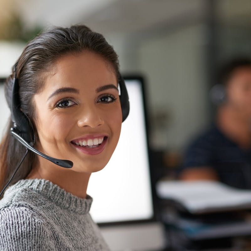 service representative at computer with headset smiling
