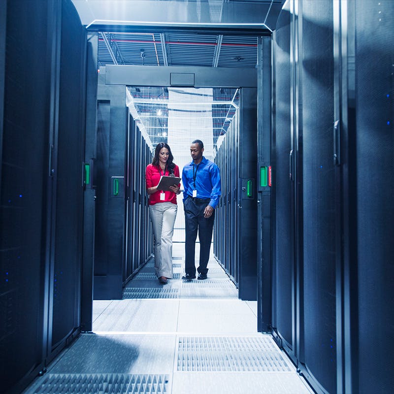 Two people waling through a server room