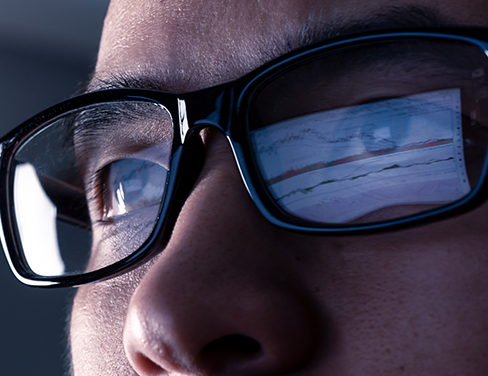 Close up image of a man in glasses looking at a computer.