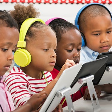 young children using tablets wearing headphones