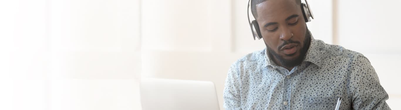 Man listening with headphones and laptop
