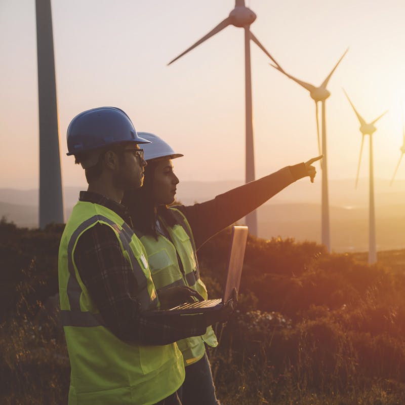 two colleagues collaborating onsite at a wind turbine farm