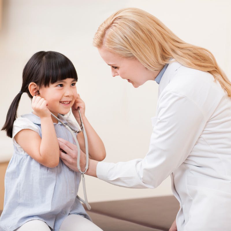 Doctor looking at child patient with mother