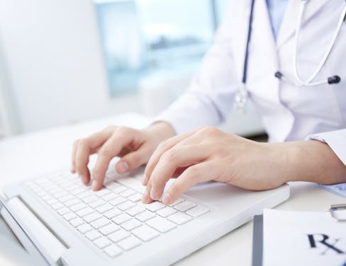 Close up of woman doctor typing on a white keyboard