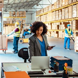Woman in warehouse working on laptop with purchase management
