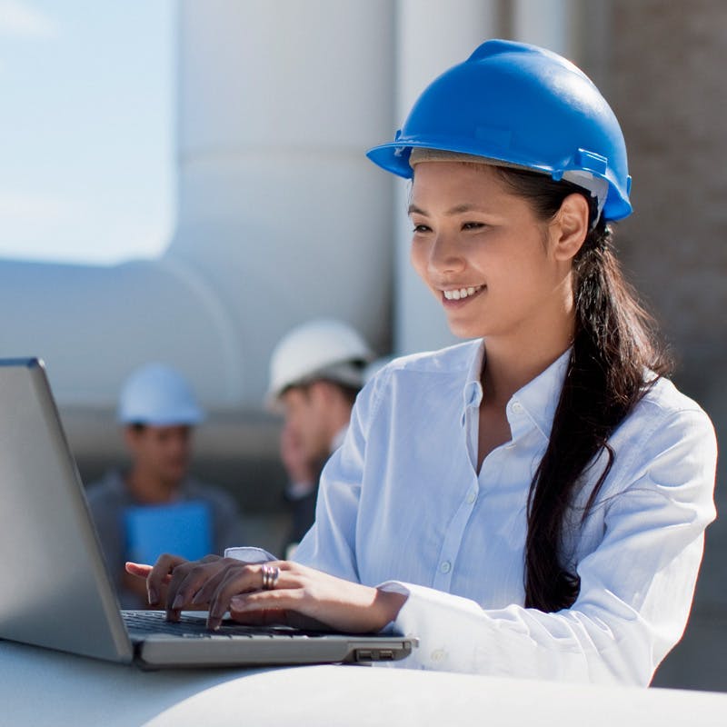 woman at a pipeline facility working on a laptop