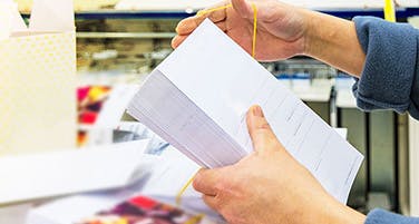 hands securing printed pages for shipping