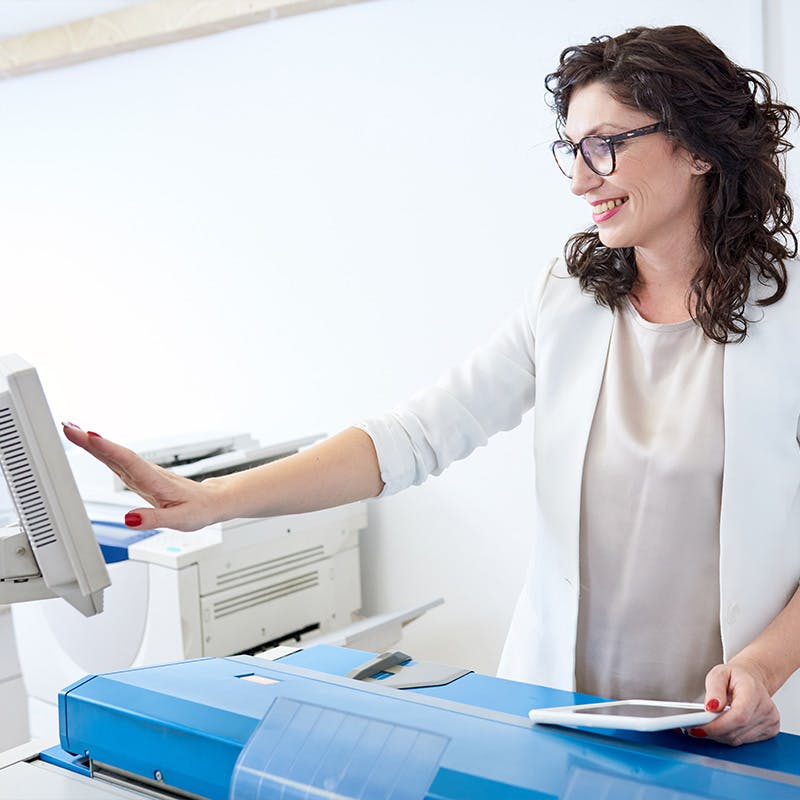 Woman using her tablet at a printer