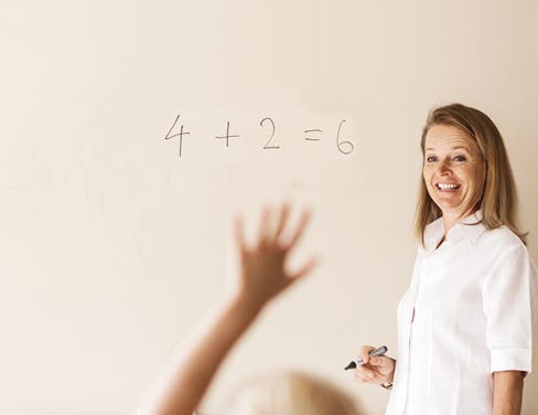 Mature teacher teaching mathematics to children in classroom