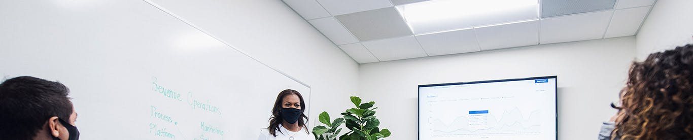 Colleagues in a meeting room wearing masks and being socially distant