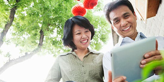 Photo of a woman and man looking at a tablet