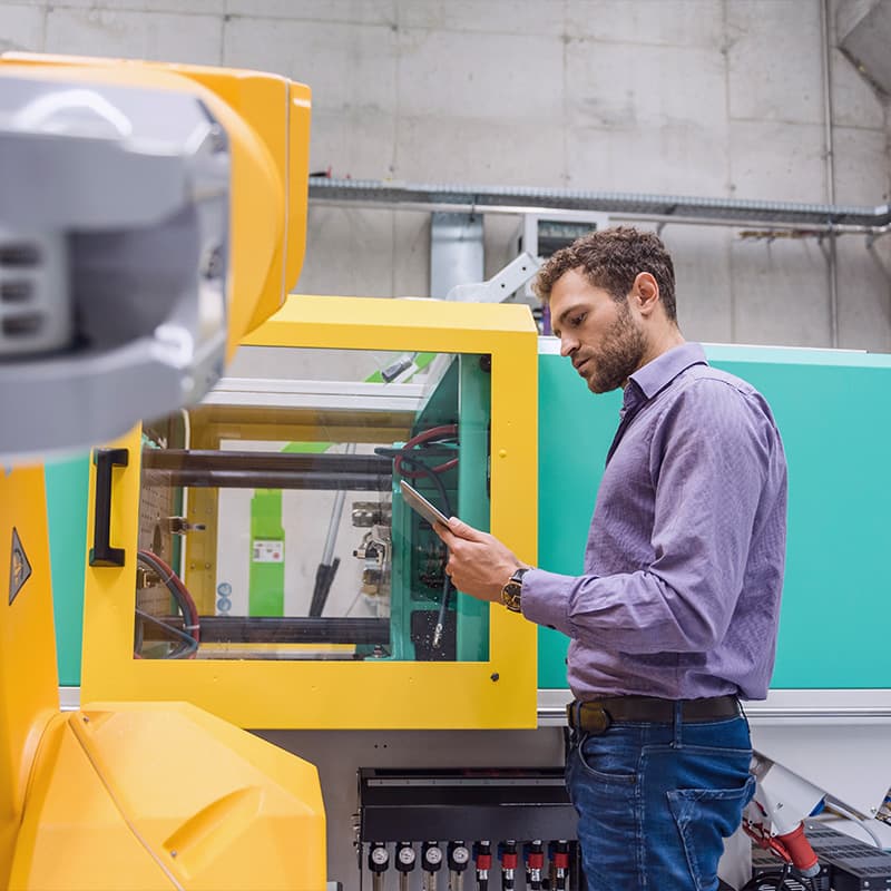 Male engineer performing maintenance on engineered automation machine in factory