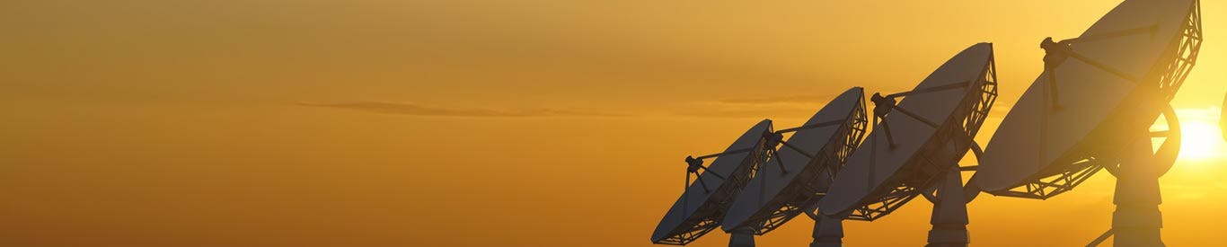 satellite dishes in a line at sunset