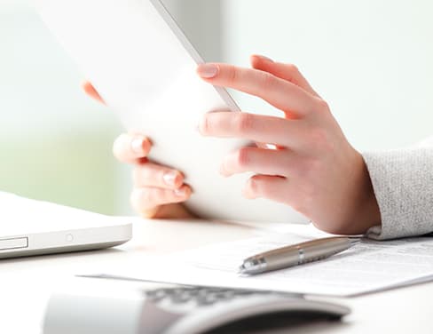 Ricoh - close-up of woman holding her tablet with calculator and pen at desk