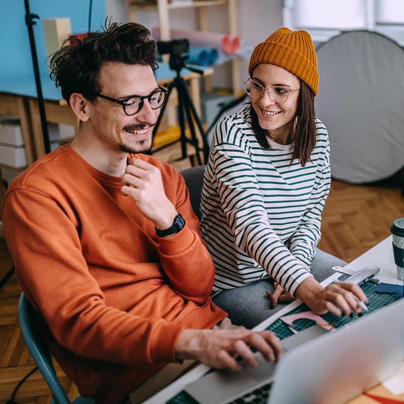Two designers discussing a project while looking at a laptop
