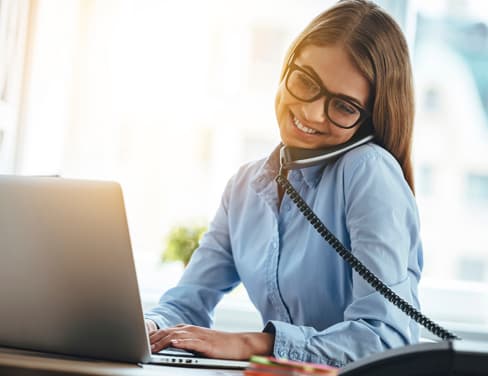 Ricoh woman on the phone at her desk on her laptop