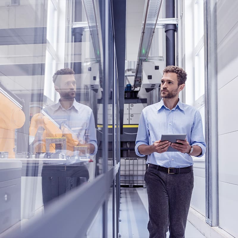 Businessman checking robots with digital tablet in high tech company