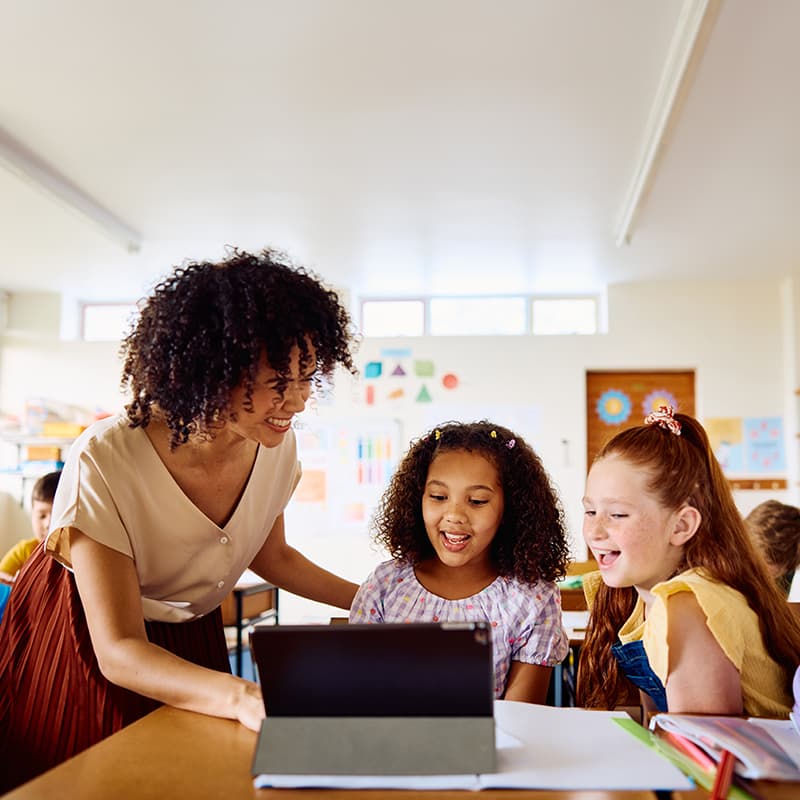 Happy teacher with two students, demonstrating how the IT system overhaul saves K-12 school district $200,000