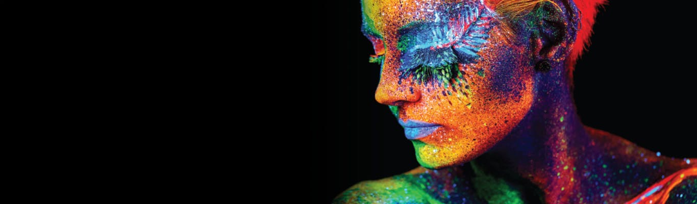 woman with painted face bold bright vivid colors on black background
