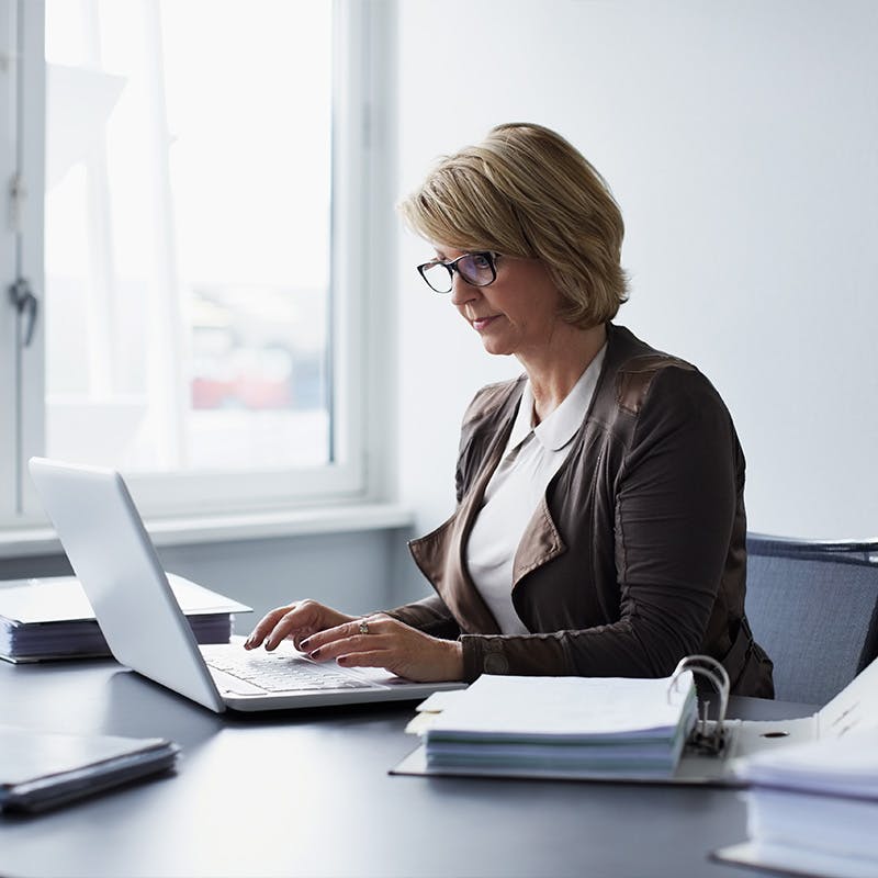 Concentrated businesswoman using laptop at desk in office