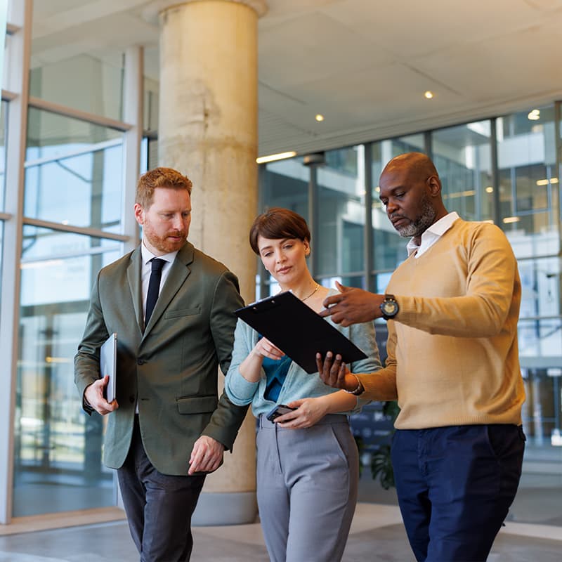 Three professionals discussing a proven operating model on a tablet, demonstrating people, processes, and service excellence.