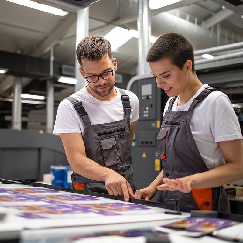 Team members working at a print facility overlooking the quality of a printed piece