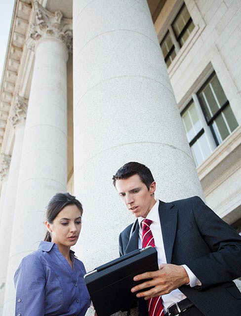 man consulting with a woman on the steps of a government building