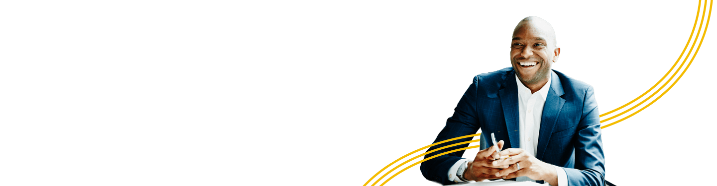 Man sitting at a table in a suite holding a mobile phone smiling