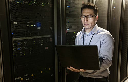 man technician doing diagnostic tests on computer servers in a large server farm