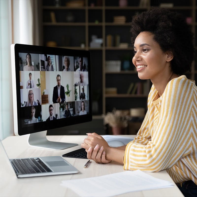 Woman working remotely, teammates are on the screen in a meeting setting