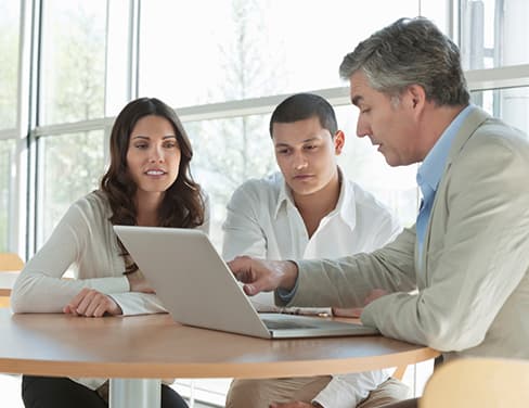 Ricoh - Gentleman advising a couple at a table with laptop