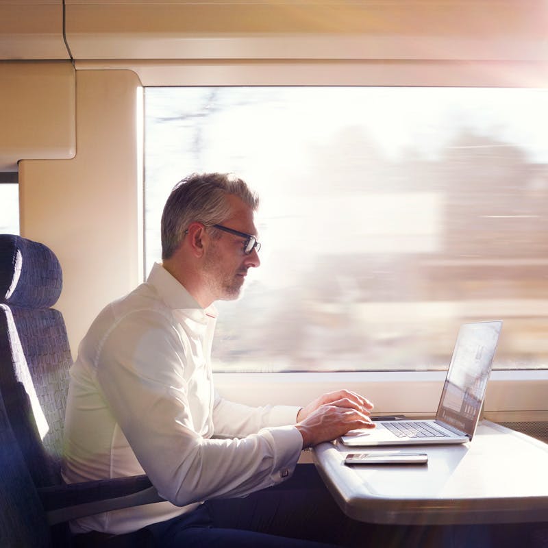 Man using a laptop computer aboard train.