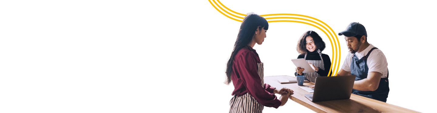 Store staff gathered around a table looking at a laptop and tablet