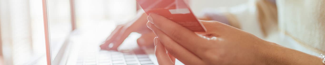 close up of hands typing on keyboard and holding credit card making online purchases