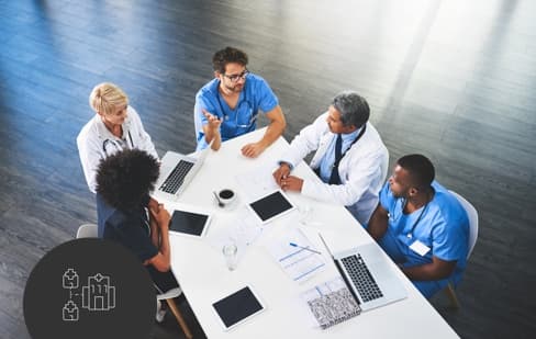 Table of hospital administration and doctors having a meeting with tablets