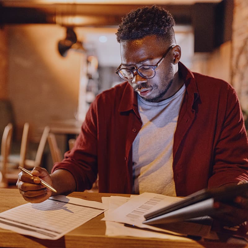 Man working at a table with paperwork and his tabler