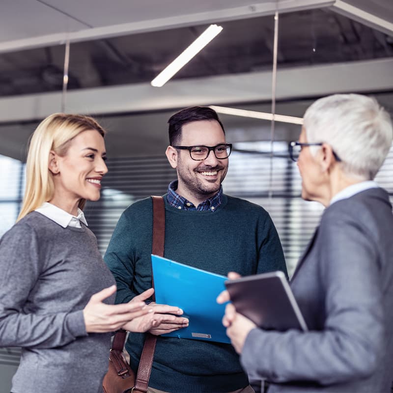 Group of happy business colleagues talking about future plans in a hallway.