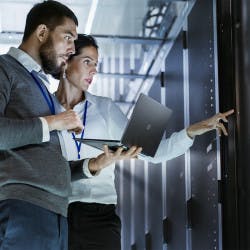 Two colleagues working on data center security in a server room