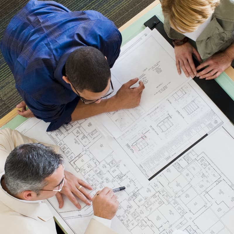architectural drawings on paper on a table and on a laptop screen