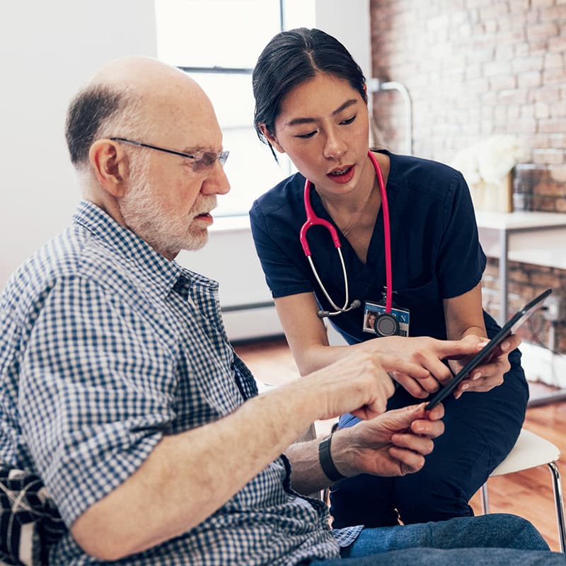 Nurse and her patient checking medical exams on a tablet and signing privacy agreement